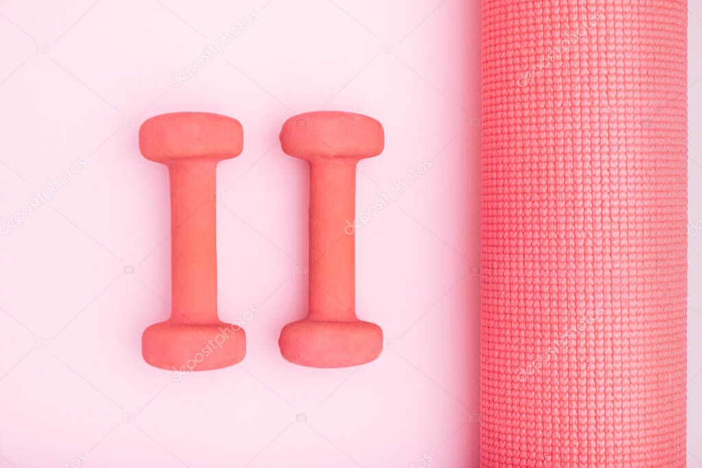 Pink exercise mats in center of light background with women's fitness yoga mat. Minimal artistic concept.