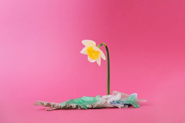 Plastik atık yığınından büyüyen üzgün çiçekli çöp konsepti. En az sanatsal.