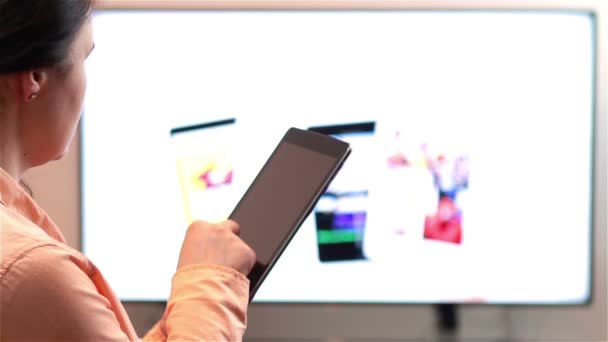 Mujer ve la televisión mientras sostiene un dispositivo de tableta — Vídeos de Stock