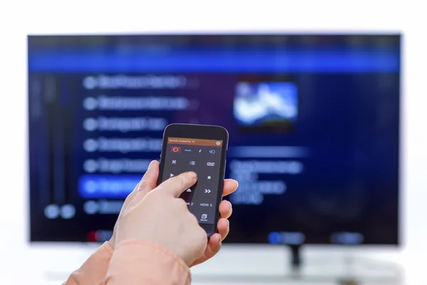 Kadın el smartphone ve kullanım uzaktan kumanda ile bir app tutarak