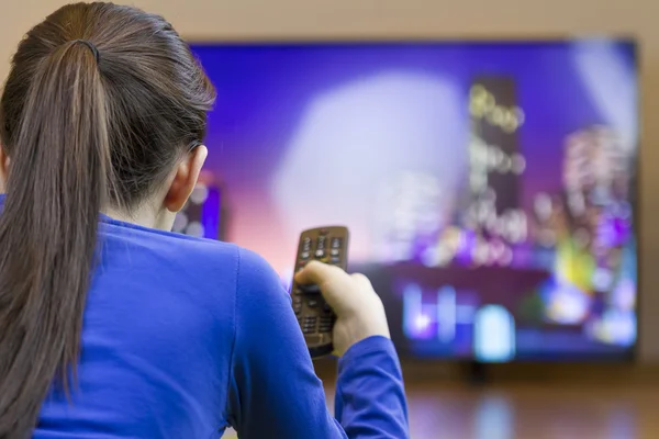 Genç kız akıllı tv izlerken uzaktan kumanda ile