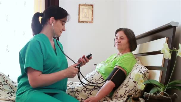 Sjuksköterska kontrollera blodtrycket till äldre kvinna — Stockvideo