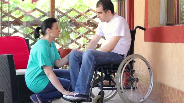 Vrouwelijke verpleegster troostende verdrietig man zit in rolstoel — Stockvideo