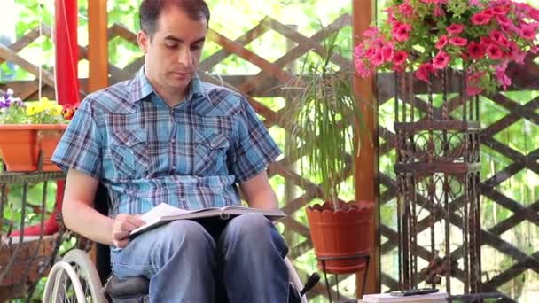 Jonge man in de rolstoel lezing — Stockvideo