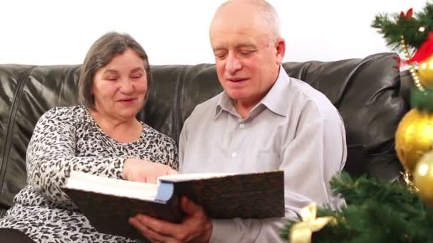 Старшая пара просматривает фотоальбом на Рождество — стоковое видео