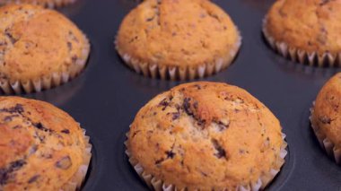 Taze pişmiş muzlu çikolatalı kekler tepside dinleniyor ve fırından çıkarılıyor. Ev yapımı, lezzetli ve rahatlatıcı bir tatlı. Mutfak projeleri, yemek tarifi videoları, fırın promosyonları, yemek blogları, yemek içeriği için mükemmel. 4k