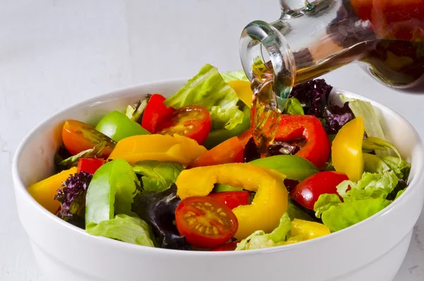 Vinegar pouring into salad bowl — Stock Photo, Image