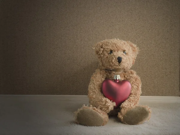 Teddybär sitzt mit rotem Herz Hintergrund — Stockfoto