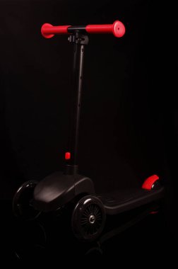 Siyah arka planda izole edilmiş çocuklar için yepyeni bir siyah scooter.