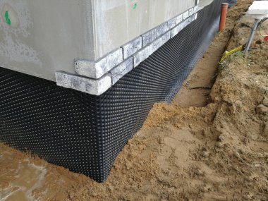 İnşaat halindeki evin temeline sabitlenmiş siyah plastik drenaj zarı