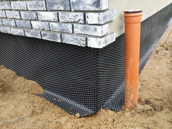 Black plastic drainage membrane fixed on the foundation of house under construction