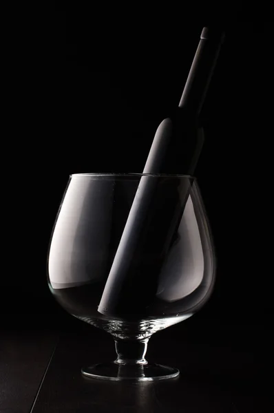 Botella de vino de vidrio negro en la enorme copa de vino — Foto de Stock