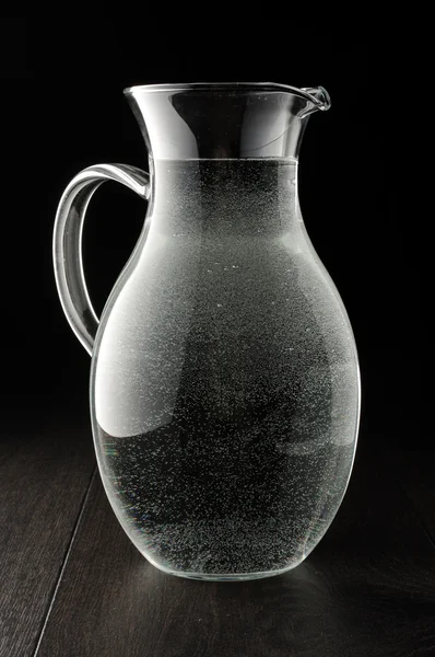 Pitcher full of drinking water on the dark background — Stock Photo, Image