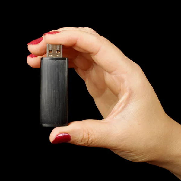 Femmina mano tenendo flash USB isolato sullo sfondo nero — Foto Stock