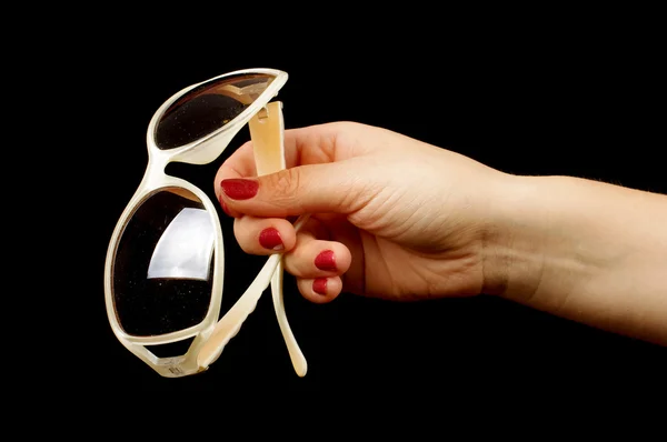 Female hand holding stylish sunglasses on the black background — Stock Photo, Image