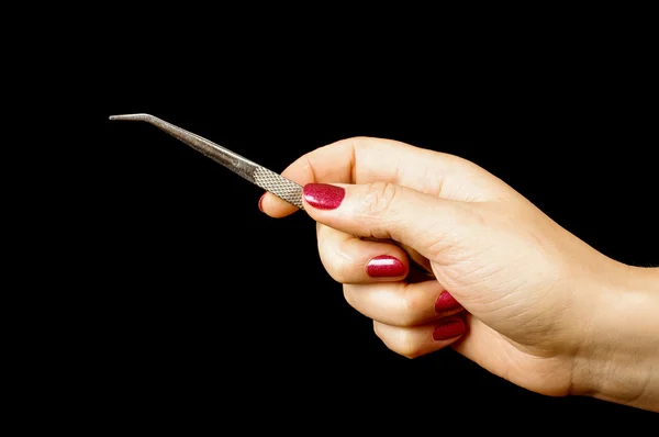 Woman hand holding tweezers isolated on the black — Stock Photo, Image