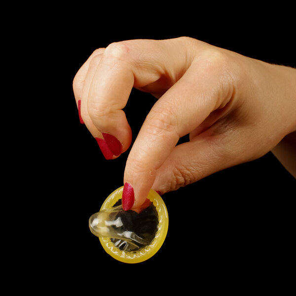 Женщина держит в руках неиспользованный презерватив
