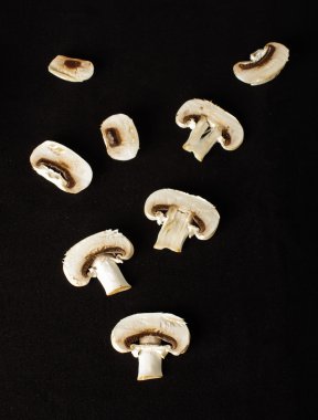 Raw champignon mushroom slices on the dark background clipart