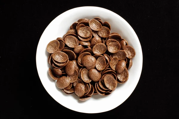 Bol de flocons de maïs croquants au chocolat croustillant isolé sur le fond noir — Photo