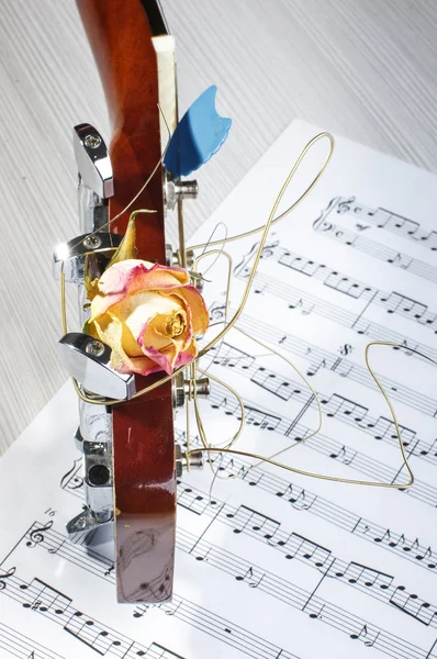 Acoustic guitar head with faded rose and sheet music — Stock Photo, Image