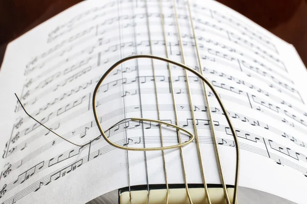 Sheet music notes paper and acoustic guitar strings — Stock Photo, Image