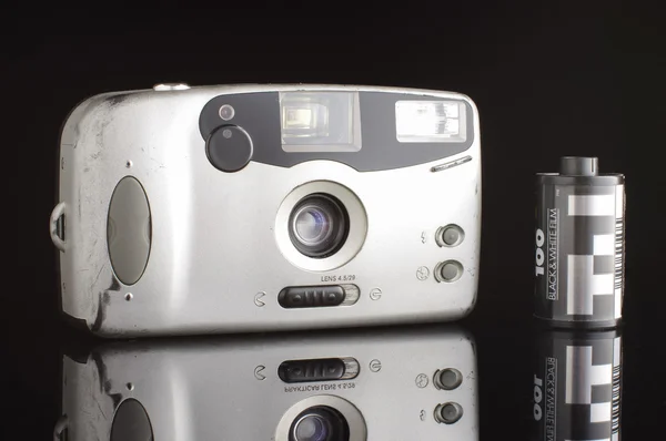 Alte zerkratzte automatische Fotokamera isoliert auf schwarzem Hintergrund mit Reflexion — Stockfoto