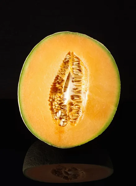 Melão melão cantaloupe na superfície reflectora preta isolada — Fotografia de Stock