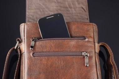 Mobile phone in the pocket of leather messenger bag clipart