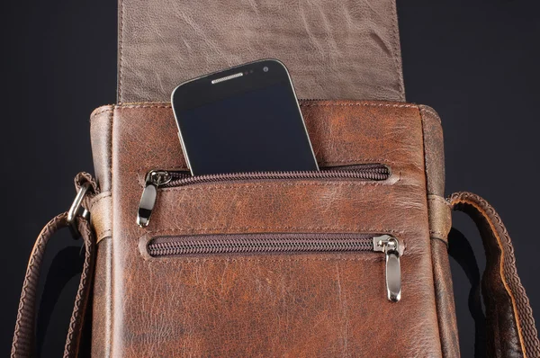 Мобильный телефон в кармане кожаной сумки курьера — стоковое фото