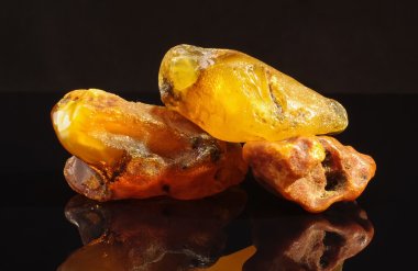 Pile of amber pieces isolated on the black reflective surface clipart