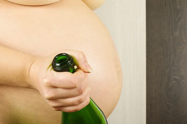 Pregnant woman holding empty sparking wine bottle — Stock Photo, Image