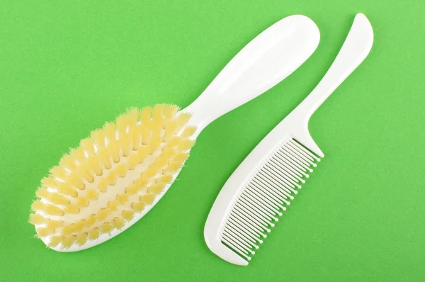 White babies hair brush and comb isolated on the green background — Stock Photo, Image