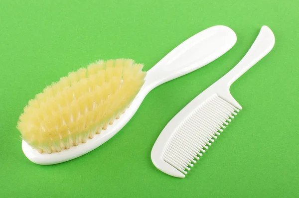 Baby hair care set of soft brush and comb isolated on the green background — Stock Photo, Image