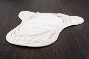 Koyu ahşap arka plan üzerinde izole doğal yeniden kullanılabilir bez bebek bezi