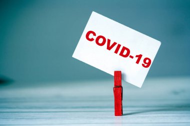 Masada kıyafet iğnesi olan yapışkan notu hatırlat. Üzerinde COVID19 yazan yapışkan bir not. Coronavirüs salgını konsepti