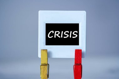 Masada tokası olan plastik çerçeve. Siyah arkaplanlı beyaz çerçeve ve yazıt kelime CRISIS. Dünya krizi konsepti