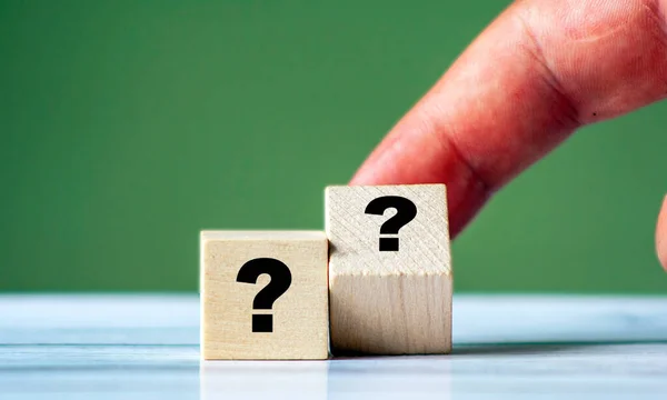 Tahta bloktaki soru işareti insan eli ya da parmağıyla. Yeni fikir ve ilham. Sınav ve destek kavramı