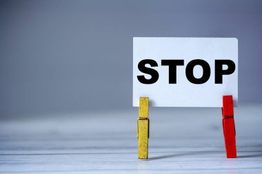 Masada kıyafet iğnesi olan yapışkan notu hatırlat. Dur sözcüğüyle yapışkan not. Tehlike uyarısı konsepti 