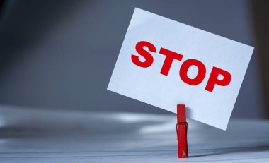 Masada kıyafet iğnesi olan yapışkan notu hatırlat. Dur sözcüğüyle yapışkan not. Tehlike uyarısı konsepti 