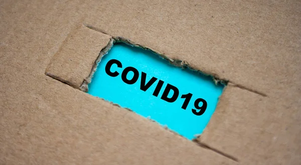 纸板纸上有一个缺口 纸下有一张写着 Covid19 Coronavirus新闻概念 — 图库照片