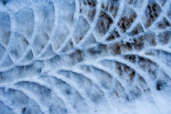 アスファルト上の雪の中で車のタイヤの斜めの痕跡 上からの眺めを閉じます アスファルト覆われた雪 危険な道路状況だ 冬の氷の上のタイヤ試験 — ストック写真