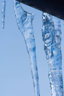 Yakın çekim buz saçağı arkaplanı. Çatıdan sarkan buz saçakları. Soğuk kış havası, kış mevsimi konsepti