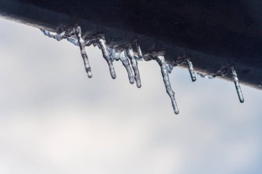 Evin çatısından sarkan uzun ve tehlikeli buz saçakları. Kış mevsimi konsepti. Buz ve kar havası kavramı