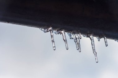 Evin çatısından sarkan buz saçakları. Kış konsepti Yakın plan tehlikeli buz sarkıtları. Donmuş iklim düzeni. Buz mevsimi