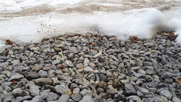 Текстура гравийной дороги покрыта снегом зимой. Камушек, щебень