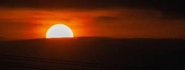 空に沈む夕日と素晴らしい雲 オレンジの太陽の盾 オレンジ色の空に銀の裏地と雲と強い日の出 — ストック写真
