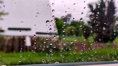 Gerçek yağmur damlaları ev camı üzerinde kayar. Şiddetli yağmur. Camdaki su damlacıklarının yakın plan görüntüsü.