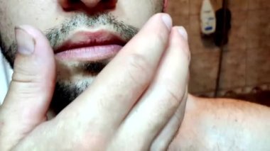 Yakışıklı bir adam sakalına dokunuyor. Genç adam eline, sakalına dokunur.. 