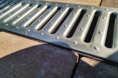 Demir drenaj ağı. Kaldırımda yağmurdan sonra su için drenaj yapın. Asfalt döşeme ve drenaj sistemlerinin kurulumu