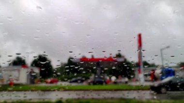 Yolda cam araba camına yağmur damlaları düşer. Yağmurlu bir günde yolda giden bulanık arabalar.
